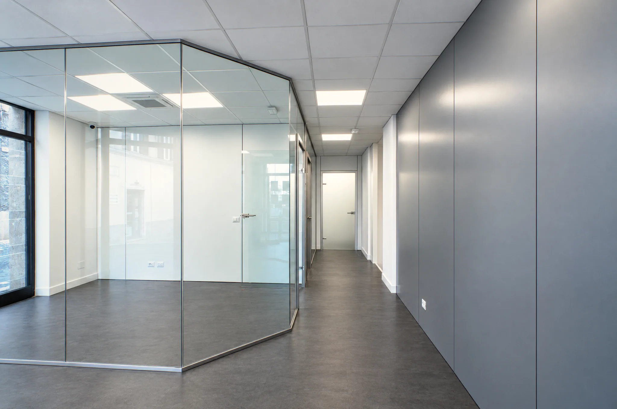 Aula chiusa da pareti in vetro con porta battente, vista dal corridoio