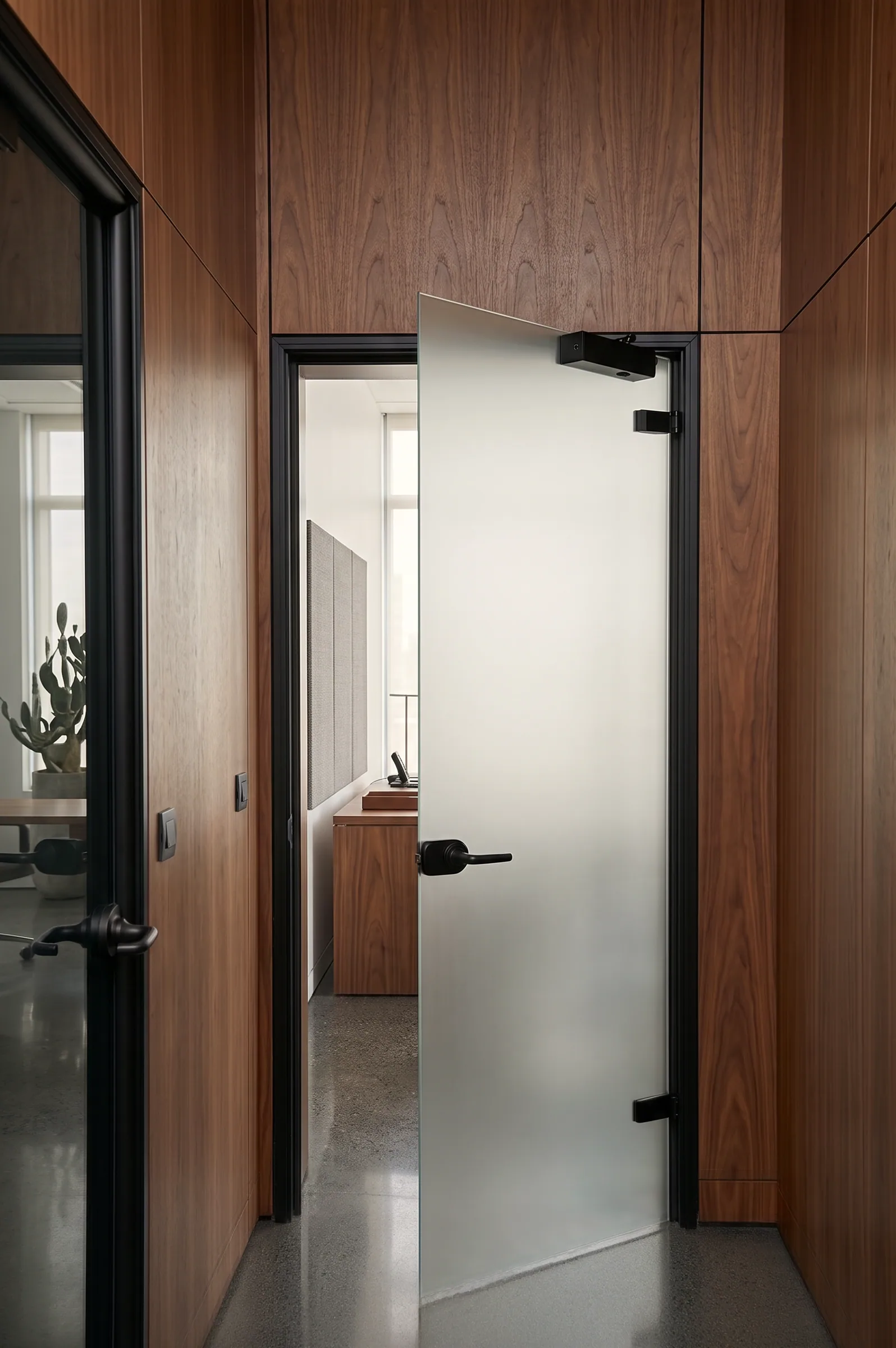 Porta a battente in vetro satinato, integrata nella parete modulare, con telaio scuro e maniglia.