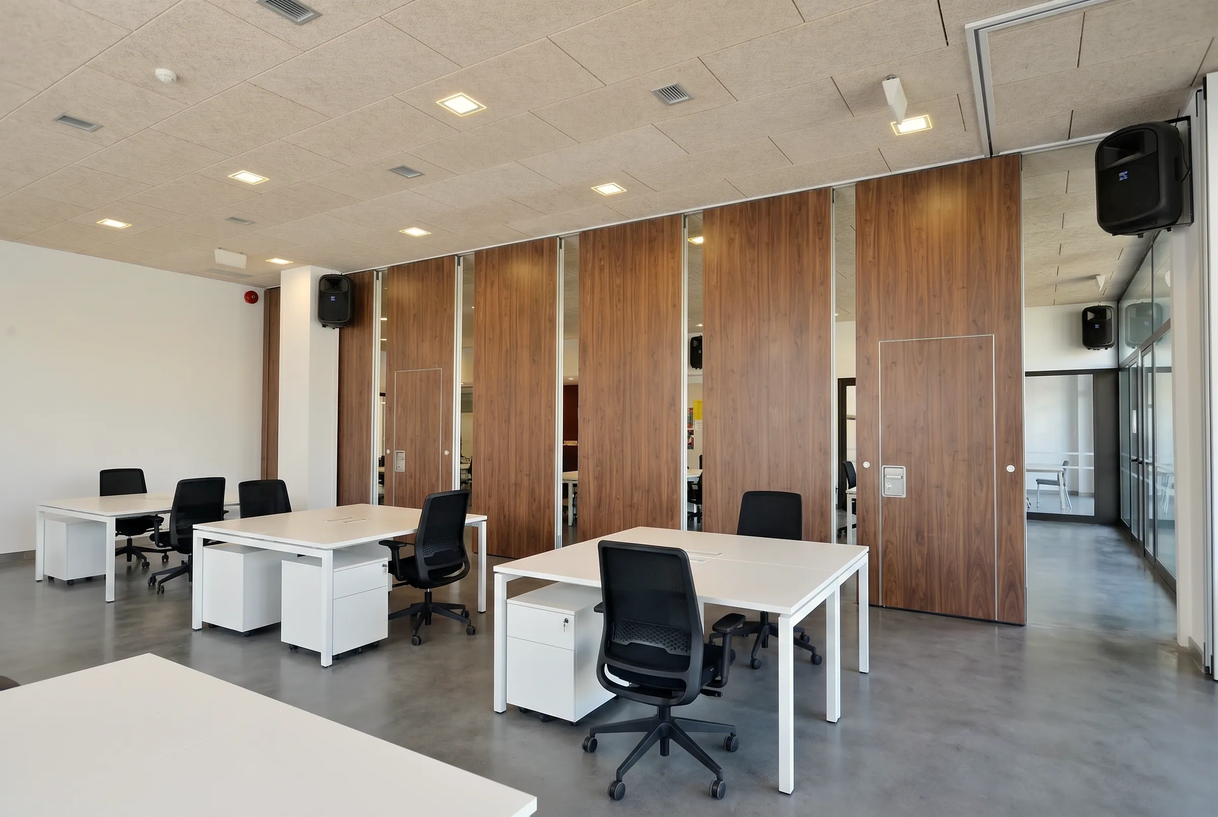 Parete manovrabile in noce chiusa, con il binario a soffitto, i pannelli affiancati e una porta pedonale