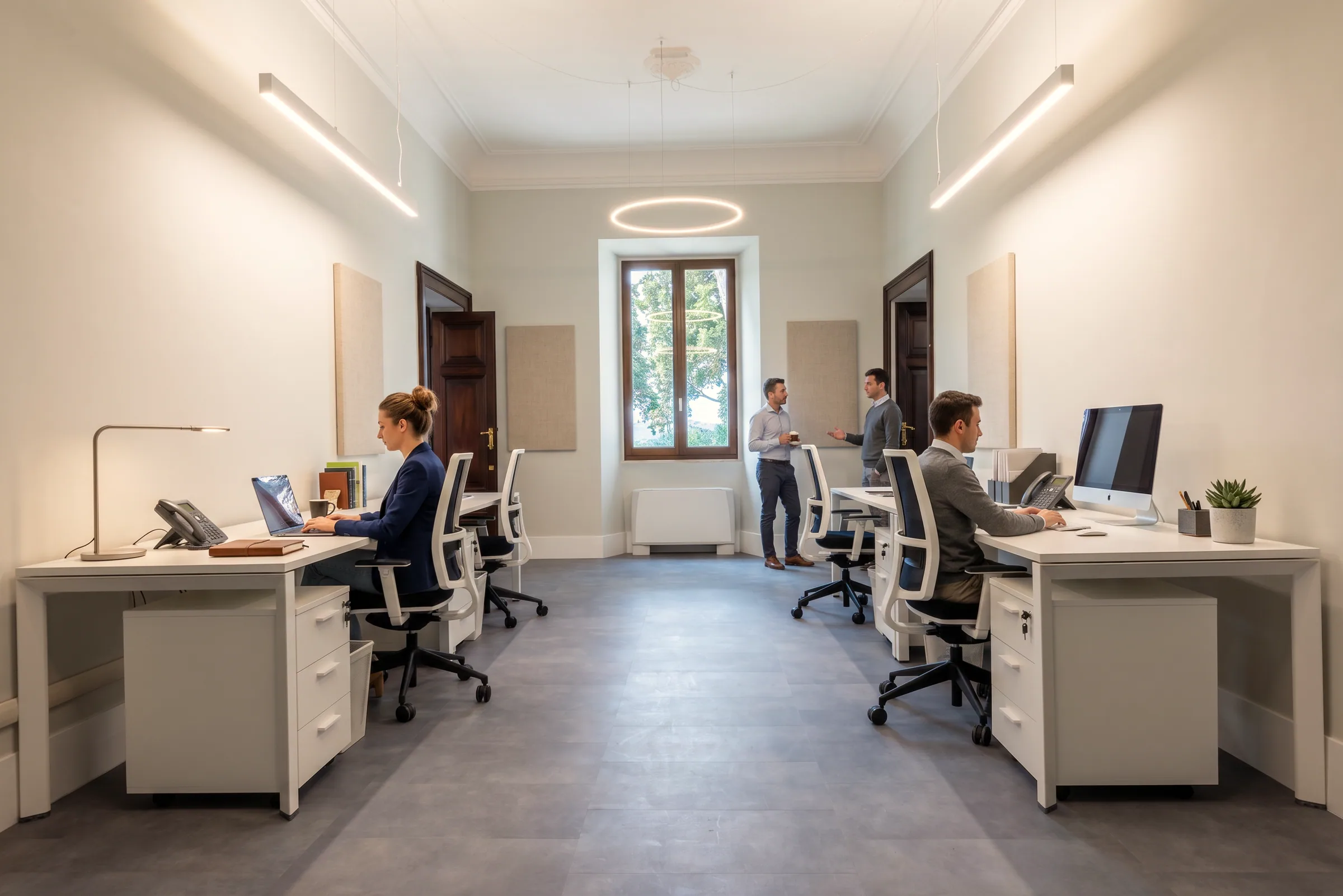 Ufficio in funzione con persone alle postazioni, in uno spazio già rinnovato con nuove pareti e nuova illuminazione